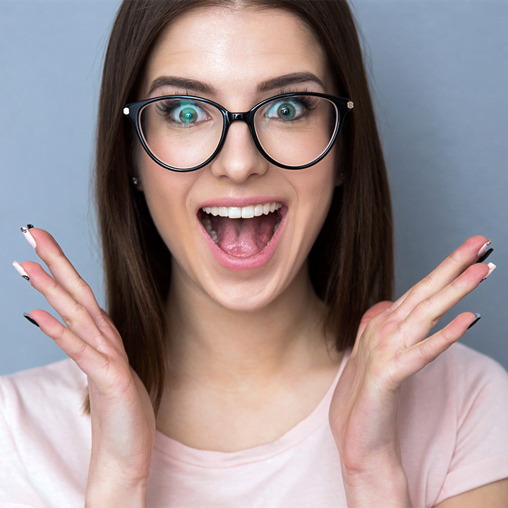 Parodontose, auch bekannt als Parodontitis oder Zahnfleischerkrankung, entwickelt sich schleichend und kann leicht übersehen werden. (Lachendes Frauengesicht mit Brille und rosa T-Shirt. Die Hände in höhe des Halses freudig nach außen gestreckt)